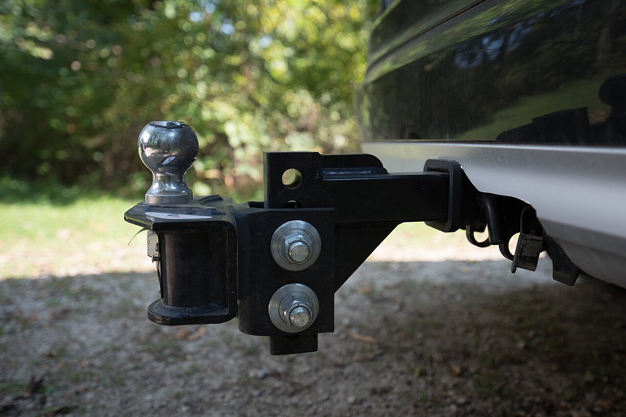Close-up of a weight-distribution hitch head with a chrome hitch ball mounted in a pickup's receiver